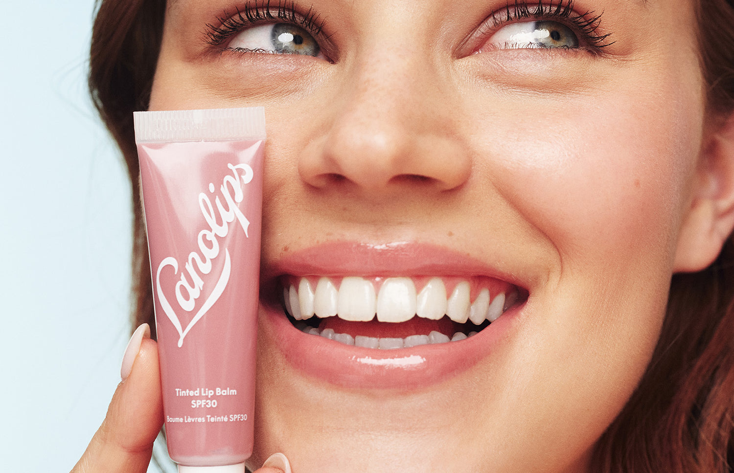 Model holding a lanolips tinted lip balm tube in her hand.